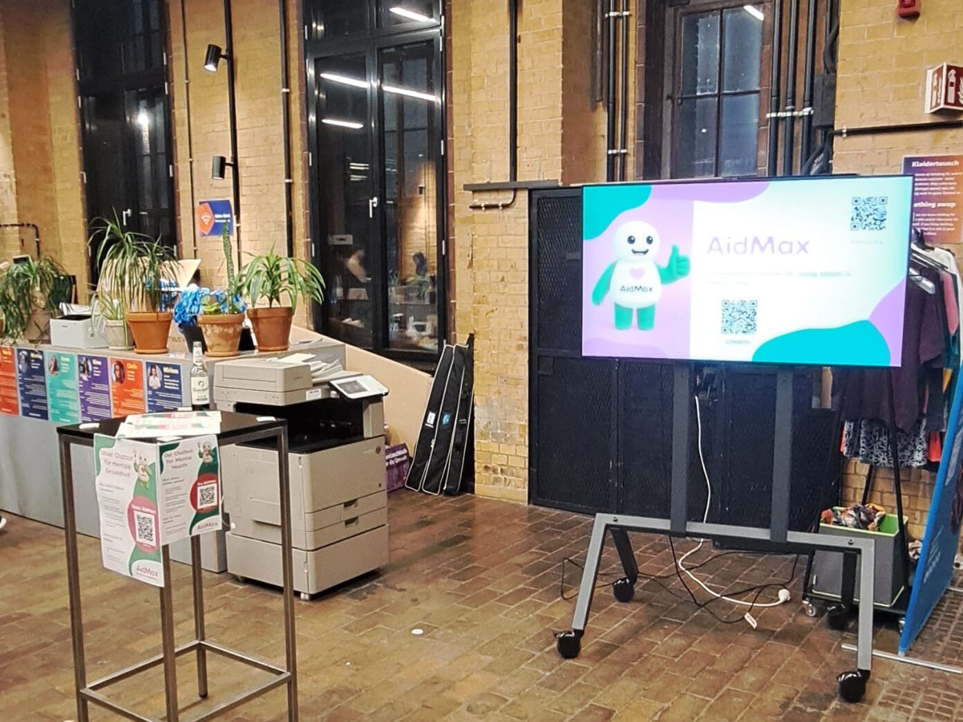 Gathering am AidMax-Stand im bUm Berlin mit Bildschirm und Infomaterial